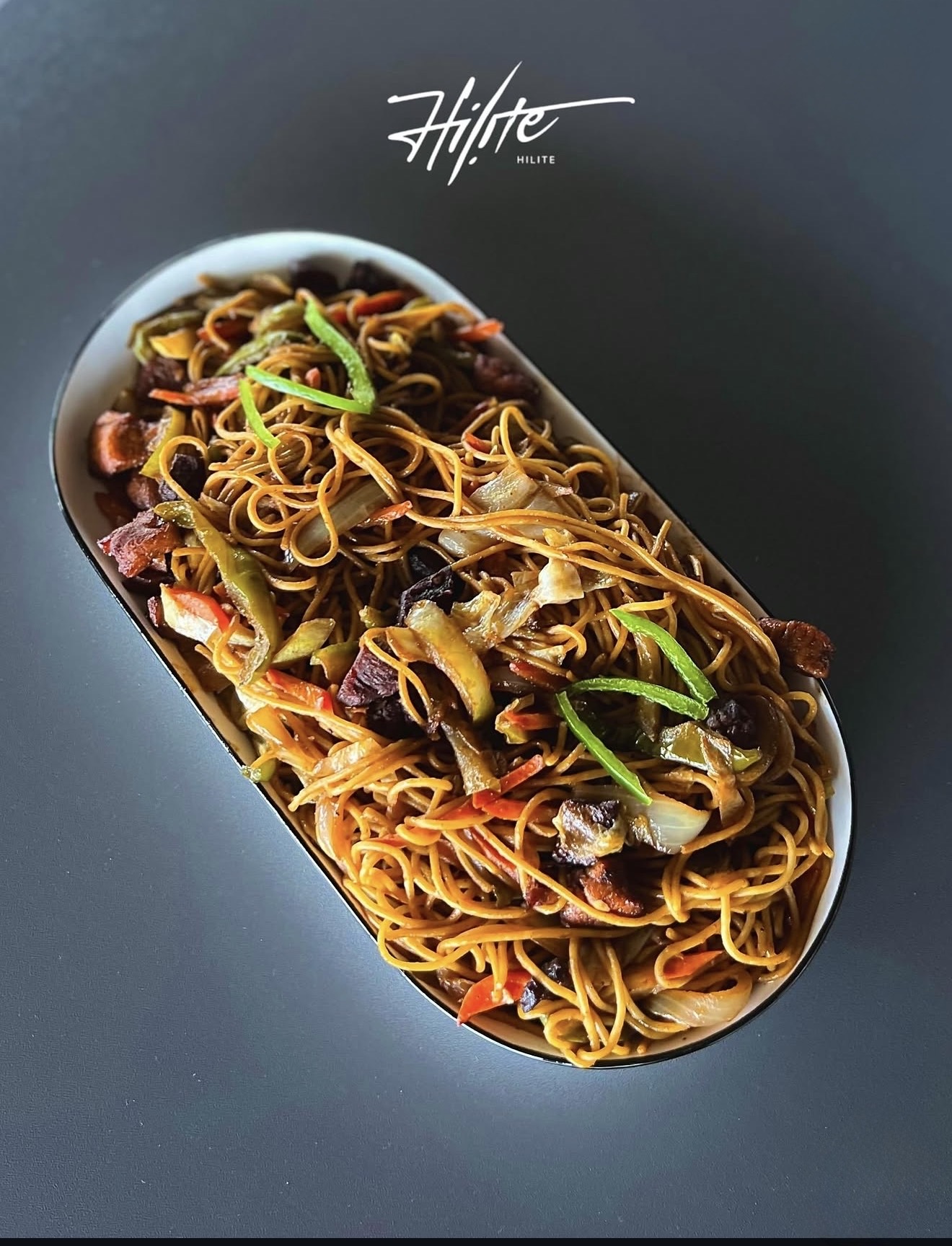HILITE stir-fried noodles with vegetables and sliced meat on a long white plate